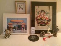 Full lot view including two framed prints, four statuettes, and black plate on a table.