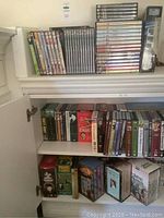 White bookcase top shelf with stacks of assorted DVD cases