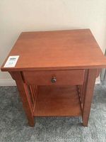 Front view of wood side table showing drawer and bottom shelf.