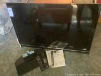 Sony Bravia 40-inch TV with remote controls, TV stand/base, and manuals on floor for sale.