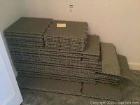 Stack of grey interlocking floor tiles against a wall
