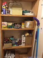 Shelves containing assorted hand tools, adhesives, WD-40 cans, and household supplies in boxes and containers