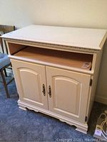 Front view of white wooden TV cabinet showing top surface, open shelf, and closed double doors with metal handles.