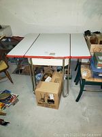 Vintage rectangular enamel table with red trim and metal legs, with pull-out sides extended