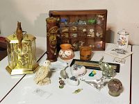 Wide shot of all lot items on display including anniversary clock, tiki figurine, ceramic covered dishes, shell figurine, elephant figurines, miniature collectibles, and letter box with Red Rose tea figurines.