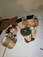 Top-down view showing front faces of the five Toby jugs with detailed facial expressions and headwear.
