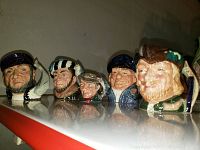 Front view of the five small ceramic Toby mugs, showing detailed character heads with hats and facial features.