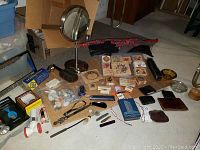 Wide view of entire lot contents arranged on floor including vanity mirror, shells, stamps, letter openers, boxes, knives, gloves and umbrellas