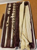 Disassembled flute (head, body, foot joints) in velvet-lined case with cleaning rod and cloth