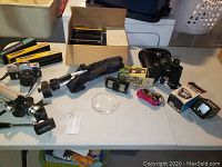 Lot items spread on a table including the Mamiya camera, binoculars, film rolls, and small accessories.