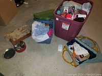 Overview of two large bins filled with assorted yarn, fabric, and sewing supplies along with some additional sewing accessories on the floor.
