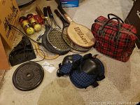 Photo of tennis racquets, knee pads, lunch bag, spice jars, and various items on floor