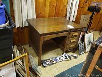View of the full solid wood desk with four drawers and a pull-out writing shelf on the right side. Visible wear and scratches on desktop surface.