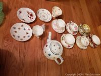 Photo of all cups, saucers and teapot displayed on floor showing assorted tea set pieces