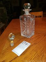 Crystal carafe with faceted stopper on table with auction tag