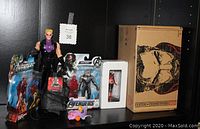 Main photo showing all items included in the lot, including action figures still in box, backpack, statuette in white box, and collector box with Thor image.