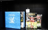 Photo showing blue padded football collectors card album, Beckett magazine, and sealed action figures of Tony Gonzalez and Brett Favre