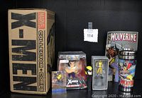 Front view of the Marvel Collector Corps X-Men box with Wolverine art, showing the collectible items inside including comic book, trading card, diecast figurines in boxes, PEZ dispenser, and travel mug.