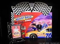 Photo showing the NASCAR and Beach Boys promotional advertisement with checkered flags, race car, and the framed backstage pass in front of it.