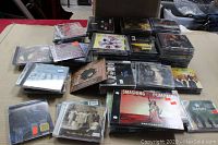 Photo showing various stacks of assorted CDs spread out on a table, includes visible album covers such as Smashing Pumpkins and John Lennon.