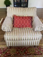 Front view of striped upholstered side chair with rolled arms and red decorative pillow