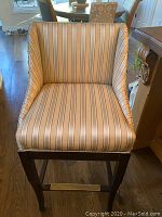 Front view of a single barstool showing striped upholstery in beige, cream, blue, and brown tones.