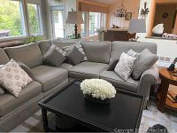 Full view of L-shaped grey sectional with decorative pillows and coffee table in front