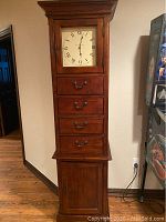 Front view of entire grandfather clock showing clock face, drawers and cabinet