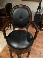 Front three-quarter view of one barstool showing seat, back, arms and base