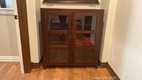Full front view of dark brown wooden cabinet with glass doors