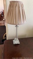 Full view of the assembled crystal table lamp with beige pleated fabric shade on a wooden surface