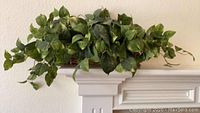 Silk greenery arranged on a white shelf, showing the overall look and length of the piece.