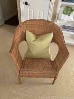 Front view of the wicker chair with green pillow on the seat.