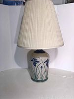 Full view of the pottery lamp with fabric shade showing floral design and lamp proportions.