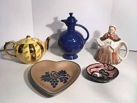 All five items displayed including Fiesta pitcher, Gibsons yellow/gold teapot, old lady teapot, Pfaltzgraff heart dish, and hand-painted bowl.