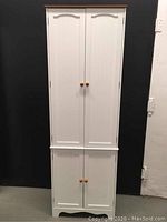 Full view of closed white cabinet showing front doors and wooden knobs.