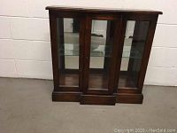 Front view of the wood and glass display case showing three glass doors and dark wood construction.