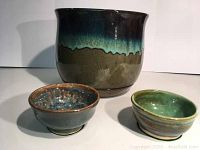 Front view of the glazed ceramic pot and two bowls showing color, glaze finish, and felt pads underneath