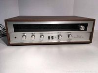 Full front view of Sansui stereo amplifier showing controls, wood case, and frequency display.