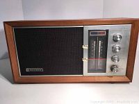 Front view of the Panasonic radio showing the wooden casing, large speaker grill, tuning display with color bands, and four control knobs.