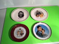 Four collectable plates displayed on a green surface including three Kennedy plates and one Monaco royalty plate.