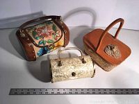 Overall view of three specialty purses: floral embroidered wooden purse, Maisstic cylinder purse, Leslie basket purse with floral decoration