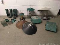 View of assortment of metal bird feeders and squirrel shields arranged on floor against wall