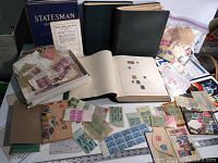 Overview showing Statesman Deluxe album (blue), two black binders, open album page with mounted stamps, loose stamps in box and bags