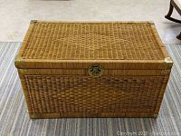 Top view of rectangular wicker trunk showing diamond woven pattern and brass corner accents.