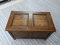 Top view of small solid wood trunk showing two rectangular panels on the lid with visible wood grain and dark finish.