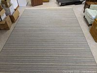 Full view of the 9 x 12 American Rug with horizontal stripes placed on concrete floor in a storage or warehouse room