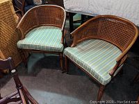 Front view of the two cane backed club chairs showing striped fabric cushions and wooden frames.