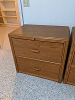 Two wood grain Sauder lateral file cabinets side by side, showing front and some side detail.