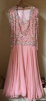 Full length view of vintage pink dress showing the full skirt and sequin top with long sleeves.